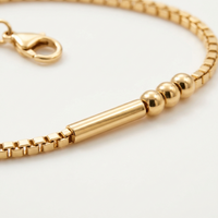 Gros plan sur les perles et la barre dorées du Bracelet Code Morse